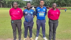Umpires Sharon Athoula and Gloria Obukor standing with officials on a cricket field during the Cricket Uganda Men’s 50 Over League match.