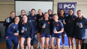 Essex women’s cricket team posing together holding cups at a PCA event indoors