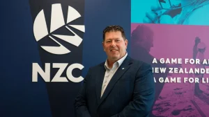 Geoff Allott standing beside New Zealand Cricket NZC logo during official announcement or administrative role context