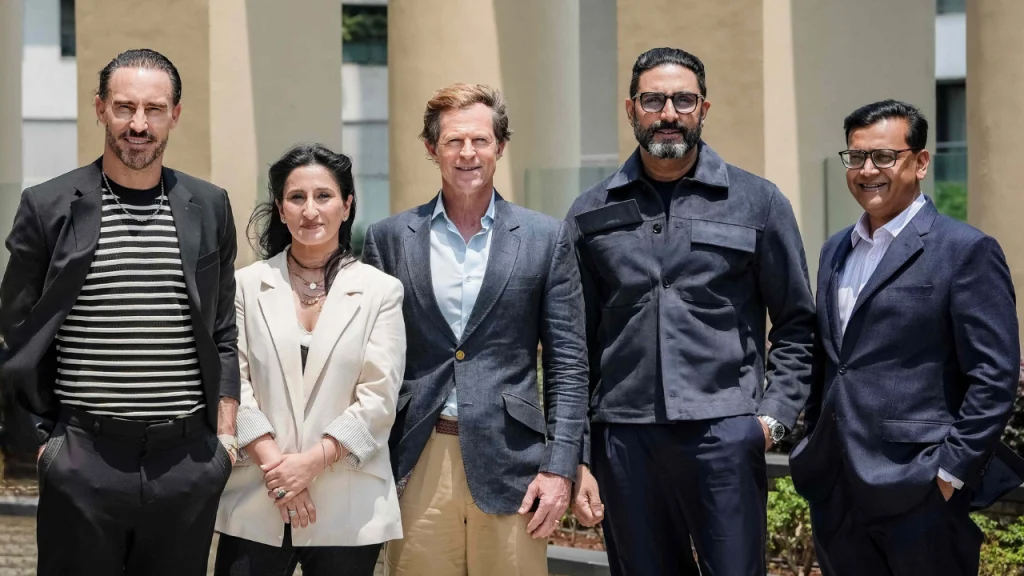 Jonty Rhodes, Faf du Plessis, Abhishek Bachchan, Priyanka Kaul, and Saurav Banerjee posing together for a group photo at an outdoor event.