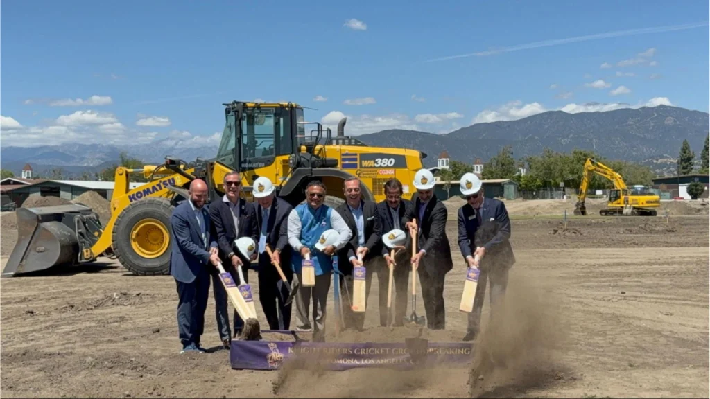 Officials breaking ground at LA Knight Riders cricket field in Pomona Los Angeles with construction equipment in background.