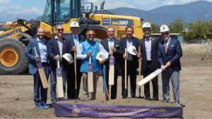 Officials at LA Knight Riders cricket ground groundbreaking ceremony in Pomona Los Angeles holding bats and helmets in front of construction site.