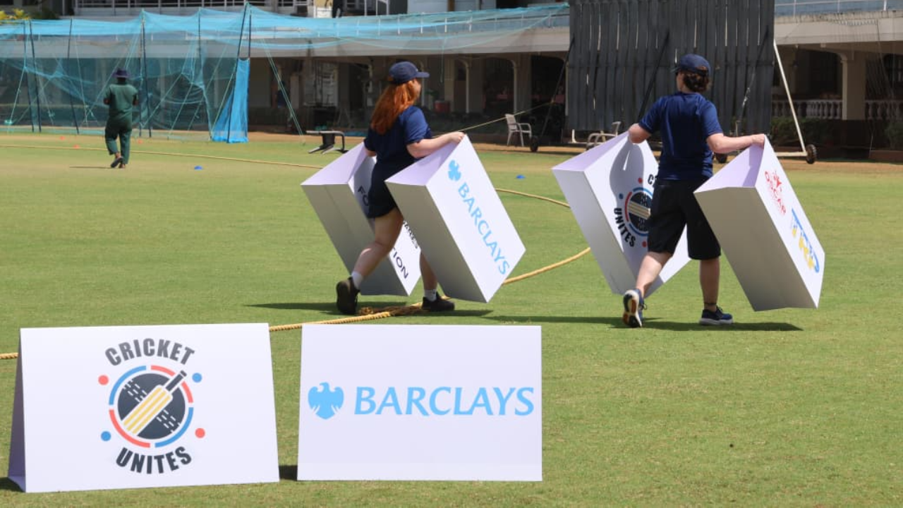 Staff carrying Cricket Unites and Barclays branded boards across a cricket training ground during MCC Foundation community initiative event