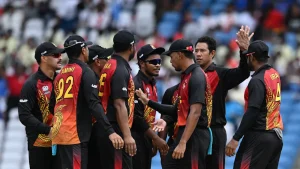 Papua New Guinea national cricket team players in a huddle celebrating during an international match in stadium.