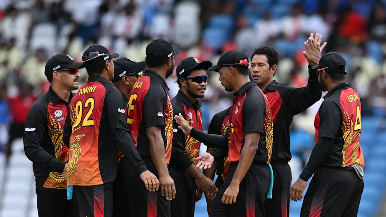 Papua New Guinea national cricket team players in a huddle celebrating during an international match in stadium.