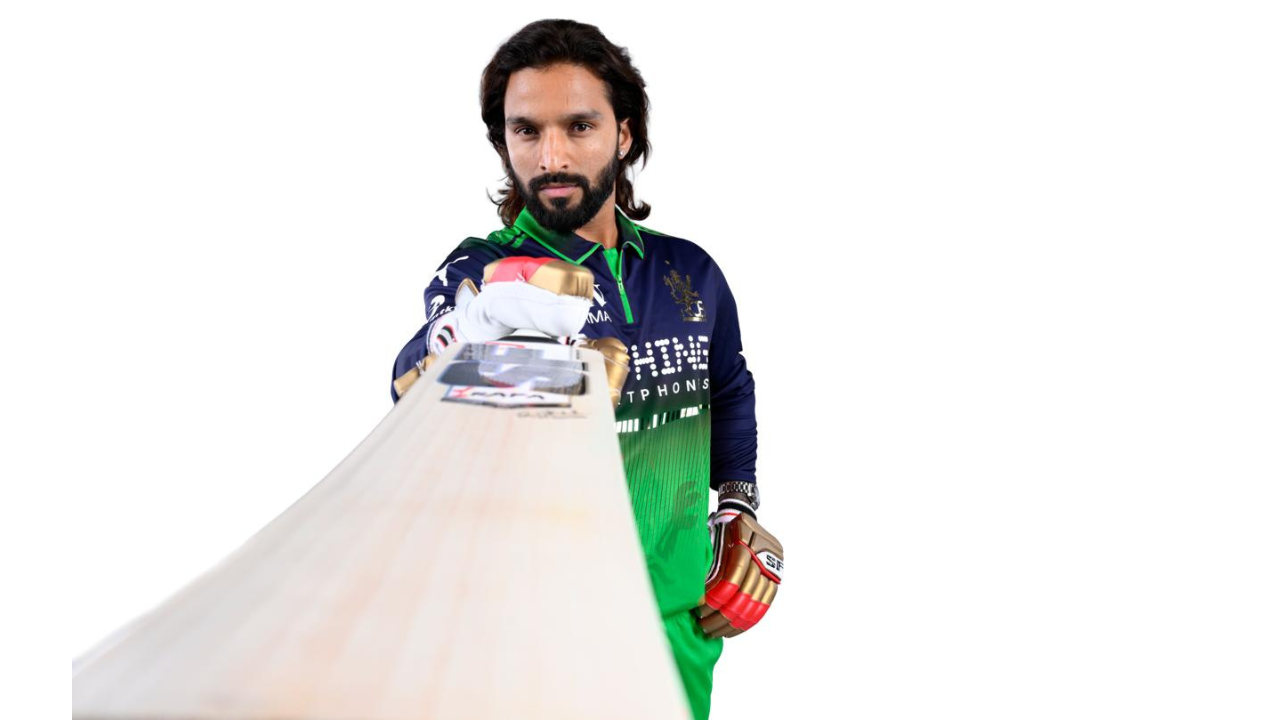 Rajat Patidar in RCB green jersey holding a cricket bat in a posed studio-style shot during IPL season