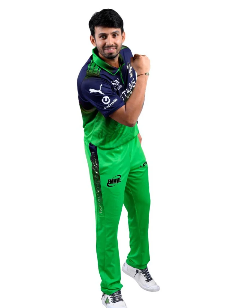 RCB player posing in green jersey during IPL photoshoot, raising arm in confident stance on white background