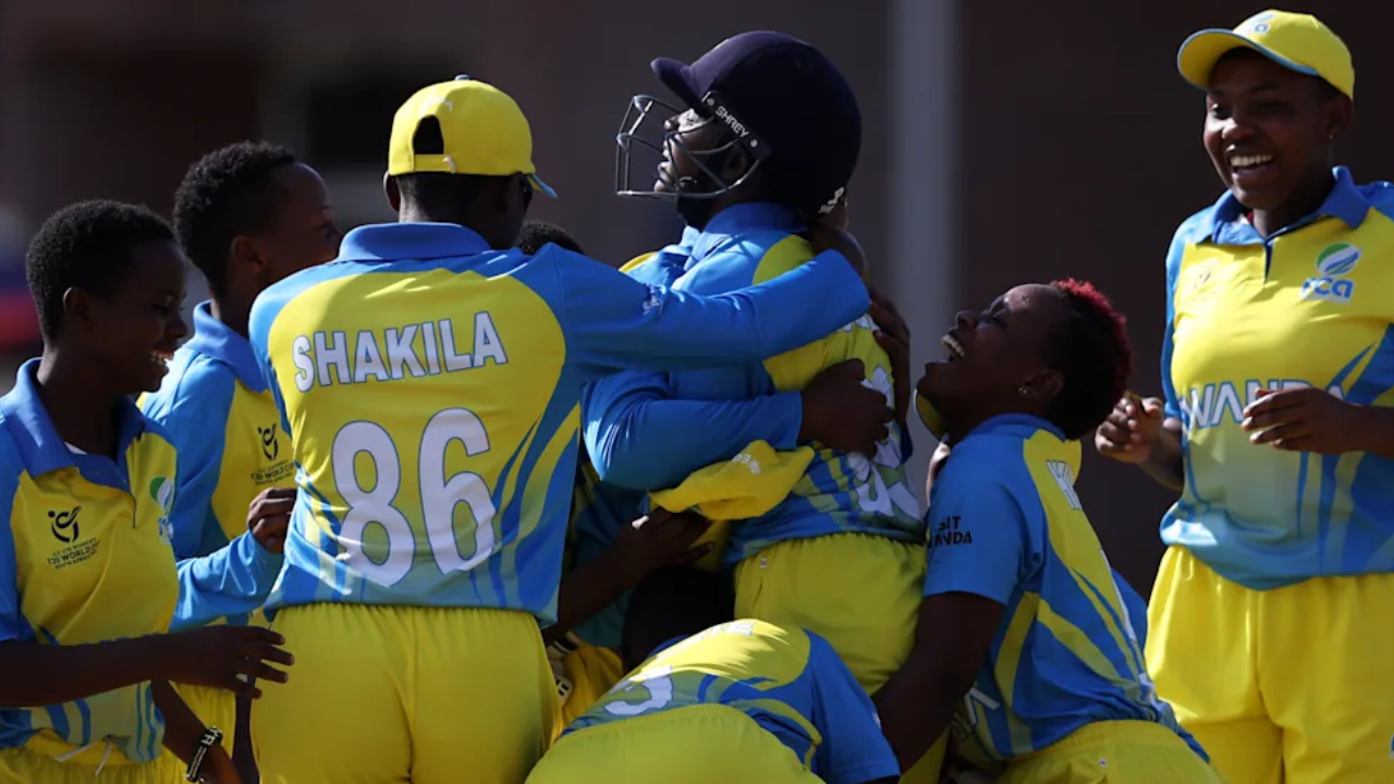 Rwanda women’s cricket team players celebrating together after a wicket during an international match in blue and yellow kits