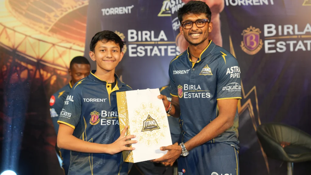 Sai Sudharsan of Gujarat Titans presenting a gift hamper to a young fan during a team event at Frizbee Food Park