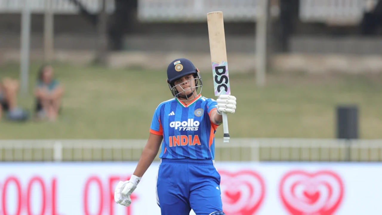 Shafali Verma raises bat in celebration while playing for India women’s cricket team in blue kit during a match