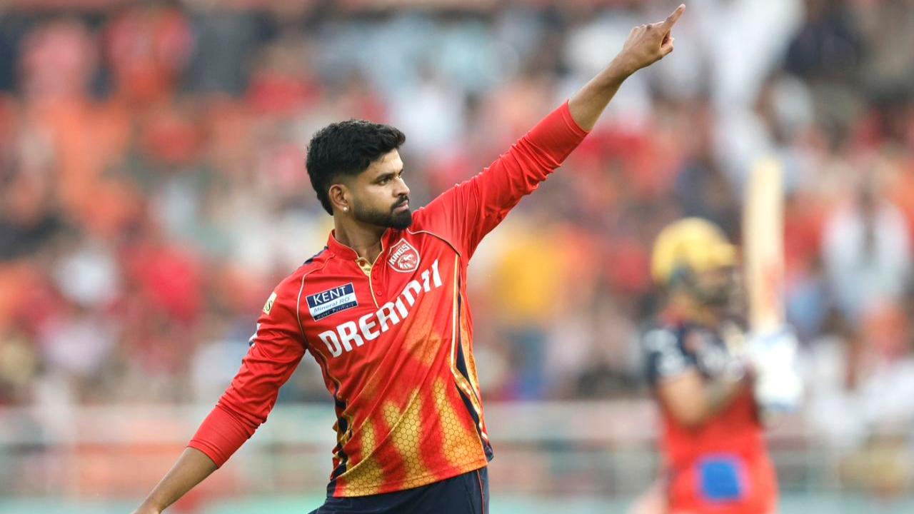 Shreyas Iyer in Punjab Kings IPL jersey pointing during match action on cricket field with blurred crowd background