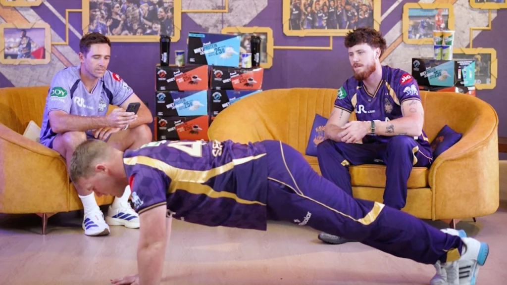 Tim Southee, Finn Allen and Tim Seifert in KKR kit during indoor team activity with player doing push-ups