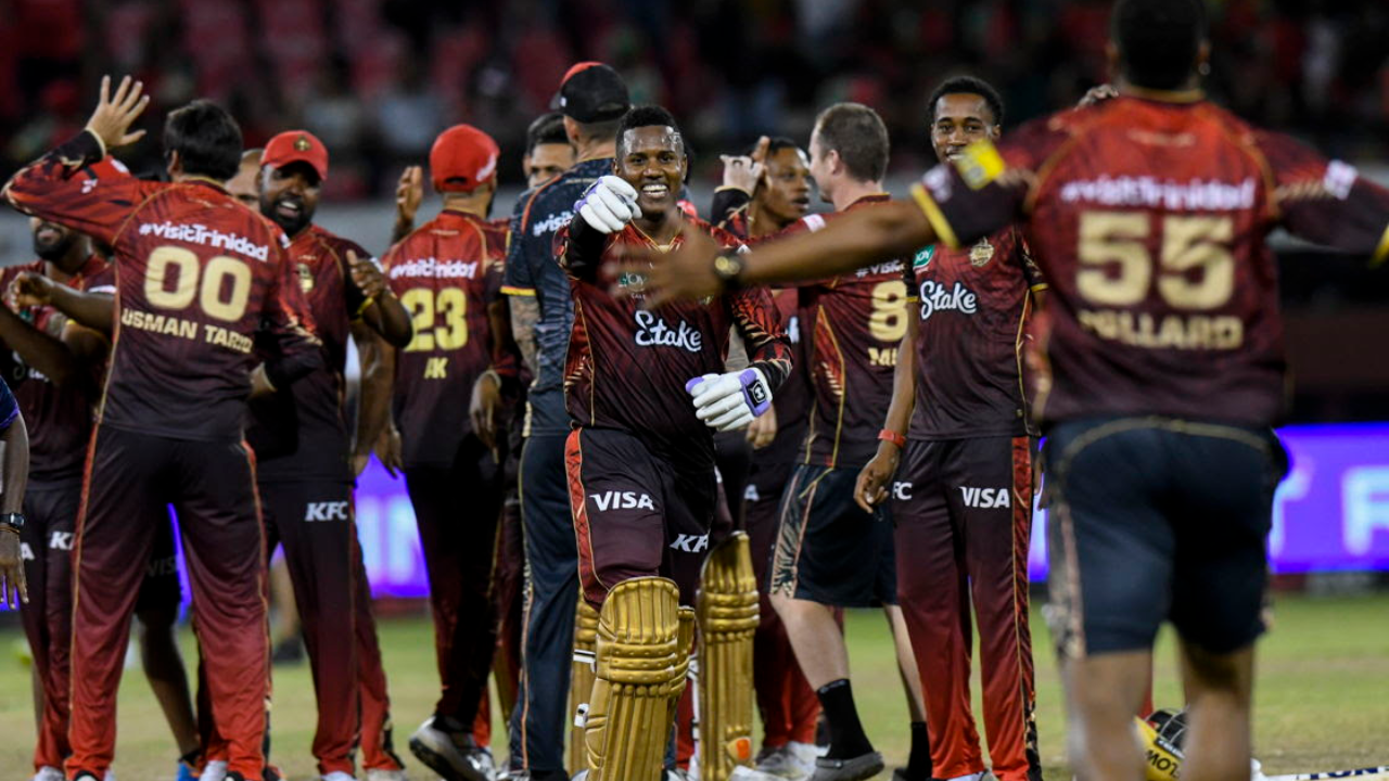 Trinidad and Tobago Knight Riders players celebrating on the field after a cricket match, with teammates in maroon uniforms congratulating each other.