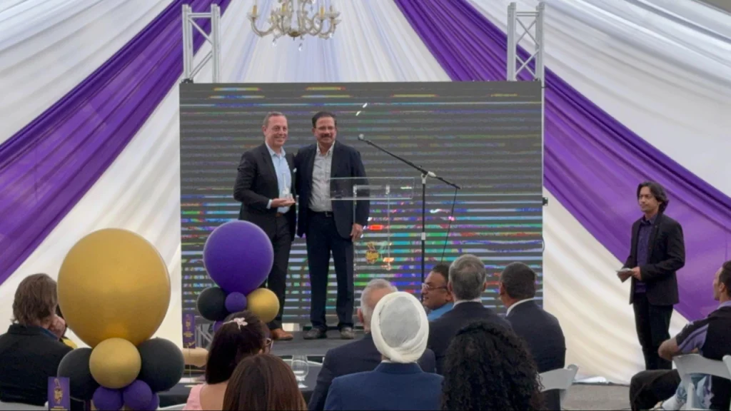 Venky Mysore and Walter Marquez on stage at Knight Riders event with audience and presentation setup.