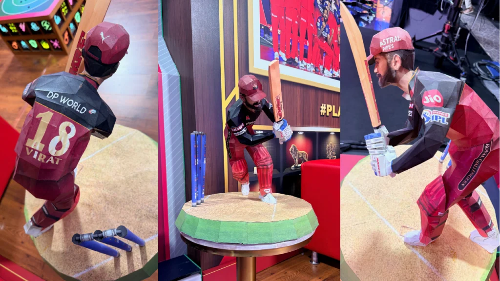 Virat Kohli themed IPL statue in RCB kit displayed in cricket studio with batting pose and stumps setup