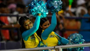 Cheerleaders performing with blue pom-poms during a Caribbean Premier League (CPL) cricket match entertainment segment.