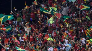 Crowd of Guyana supporters waving flags and cheering during a Caribbean Premier League (CPL) cricket match in a packed stadium.