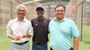 Cricket Uganda chairman Kavuma poses with Omtex ICWC Institute founder Raut and director Vijay at an indoor cricket facility following partnership discussions focused on cricket development in Uganda.