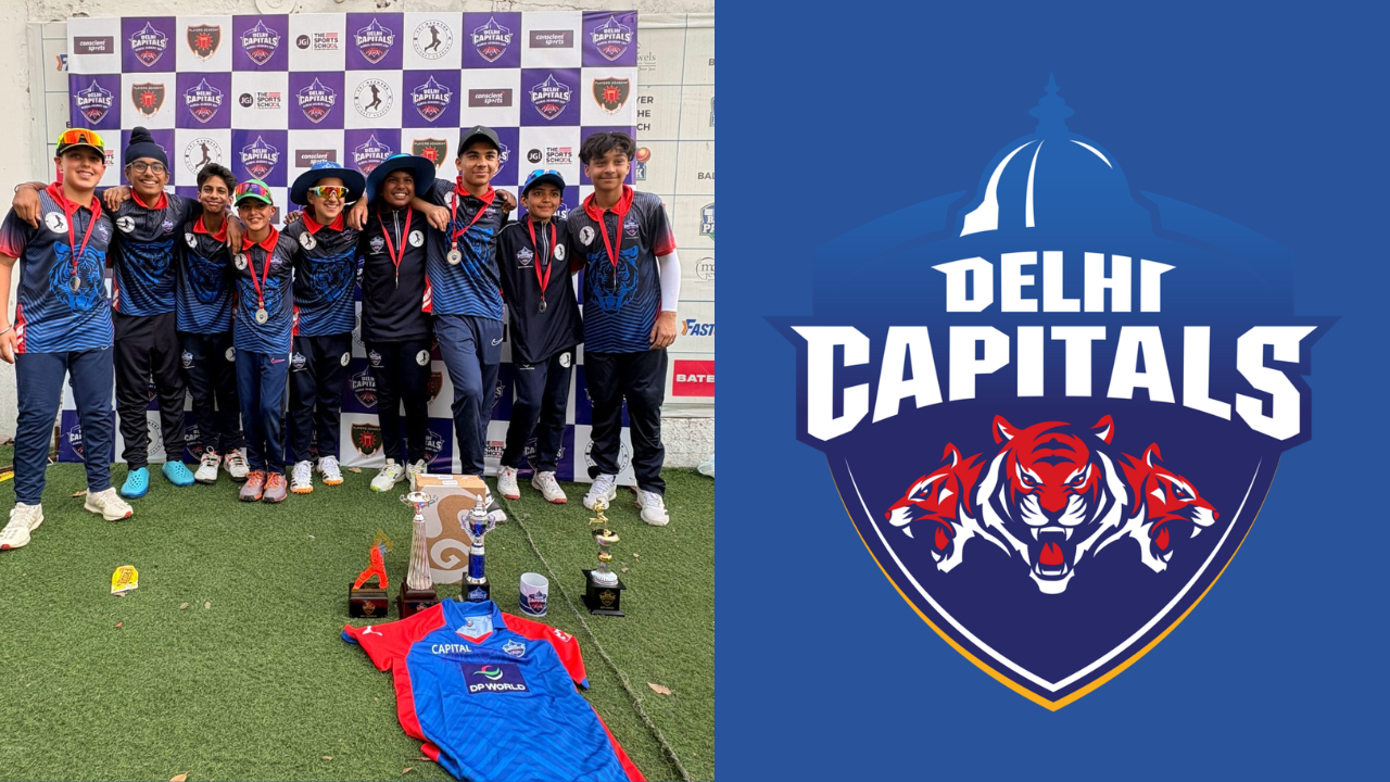 Young players from the Delhi Capitals Academy pose with trophies and medals alongside the Delhi Capitals logo after a youth cricket tournament.