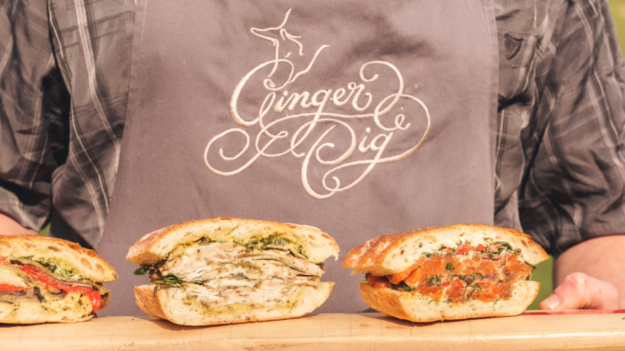Ginger Pig gourmet sandwiches displayed on a wooden board with fresh artisan fillings including chicken, salmon, and roasted vegetables.