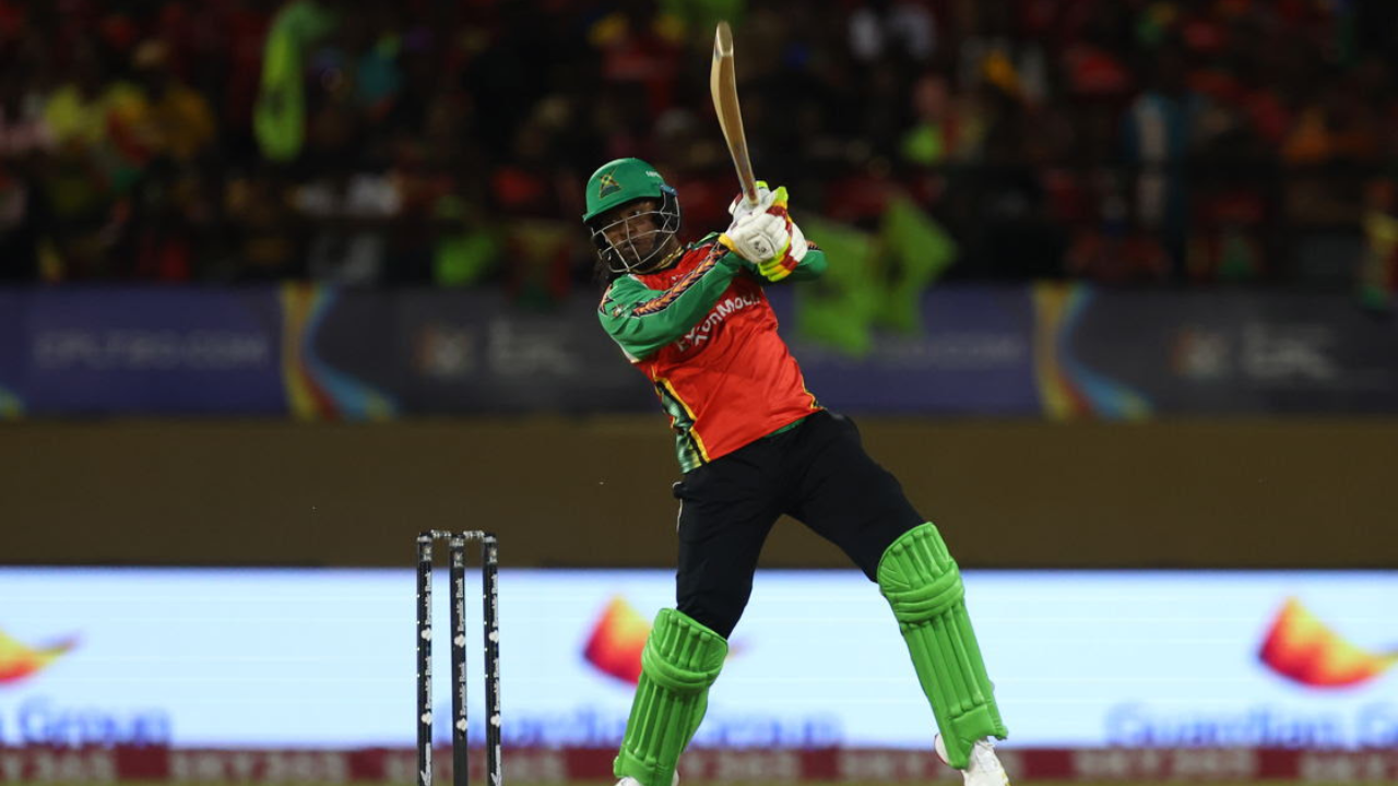 Guyana Amazon Warriors batter plays an attacking shot during a Caribbean Premier League match with fans in the background.
