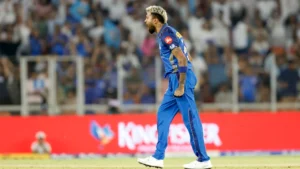 Hardik Pandya celebrating during an IPL match while wearing the Mumbai Indians jersey on the cricket field with spectators in the background.