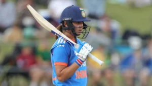 India women’s cricket captain Harmanpreet Kaur walking with her bat during a match while wearing the Indian team jersey and helmet.