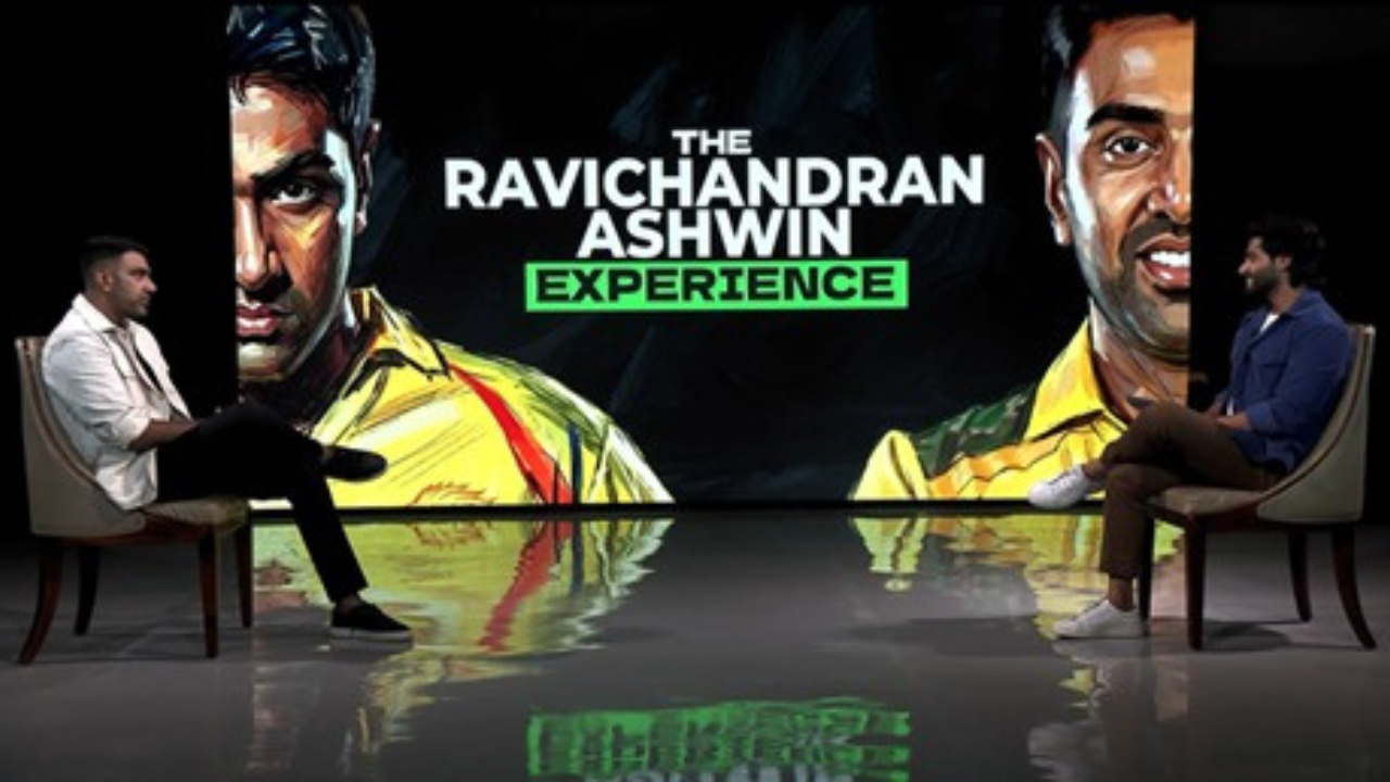 Ravichandran Ashwin interview show set with two hosts seated facing each other and large backdrop graphic reading The Ravichandran Ashwin Experience