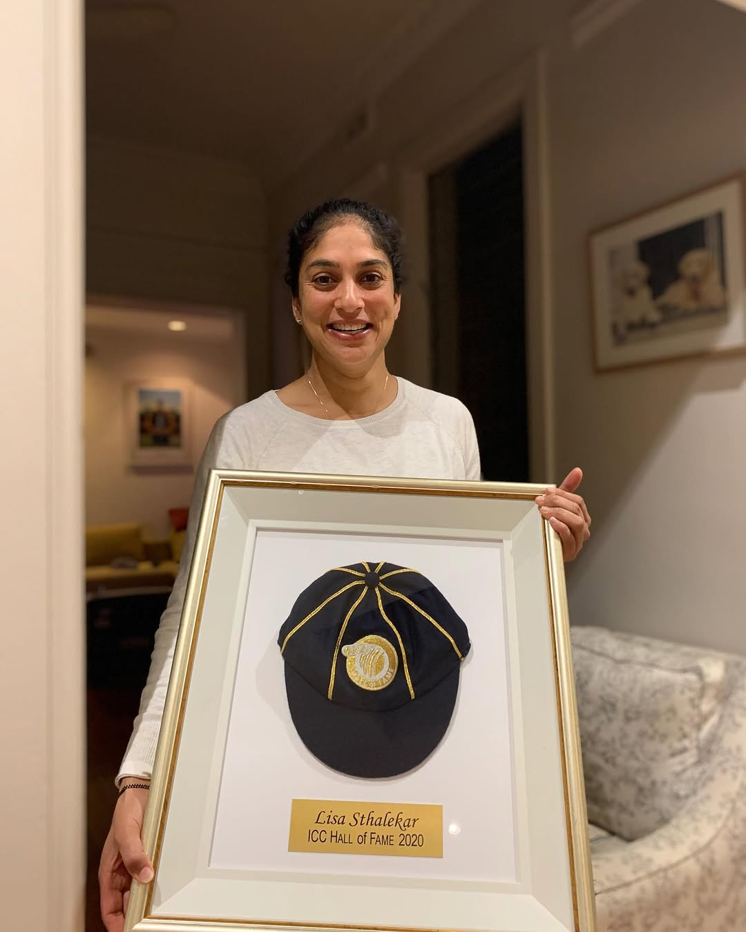Former Australia cricketer Lisa Sthalekar holding her framed ICC Hall of Fame 2020 commemorative cap presentation at home.