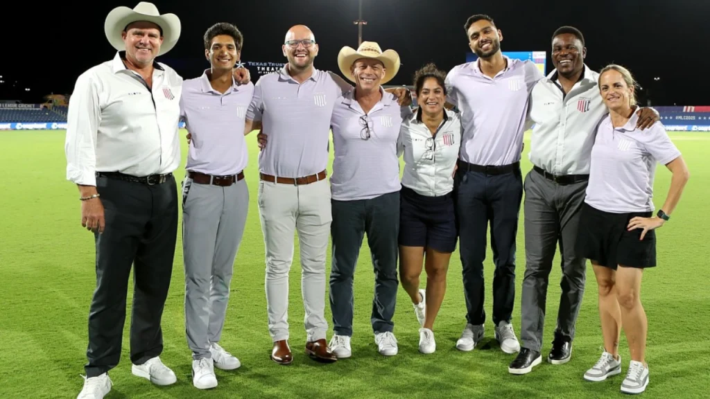 Former Australia cricketer Lisa Sthalekar posing with the Major League Cricket (MLC) commentary and broadcast team on the field during a night match.