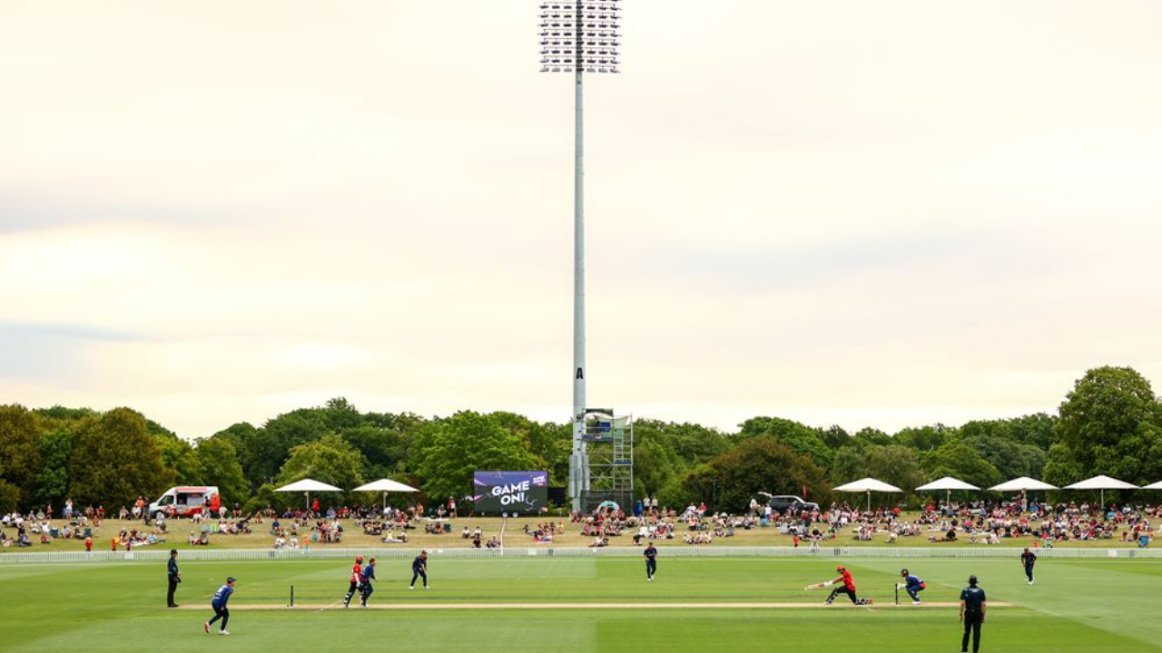 Players in action during a New Zealand domestic T20 cricket match at a packed outdoor stadium with spectators in the background.