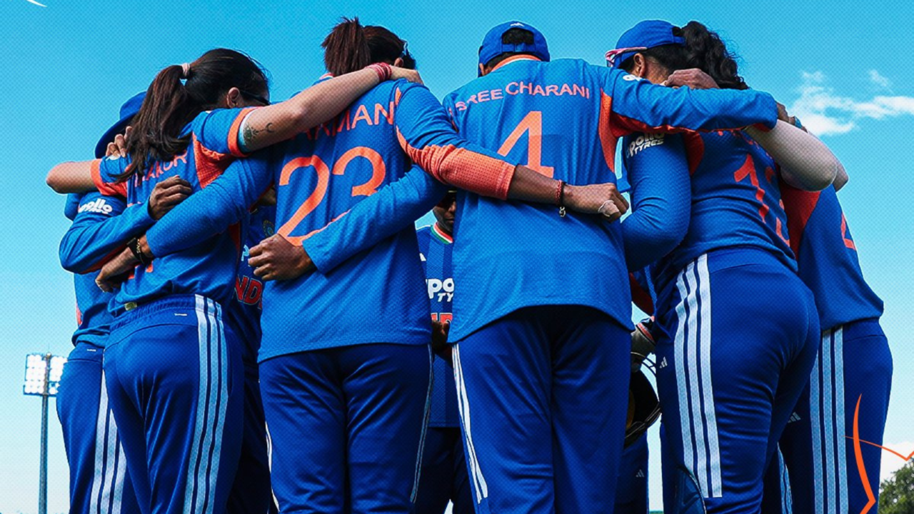 India women’s cricket team players in blue jerseys standing in a huddle on the field during a match strategy discussion