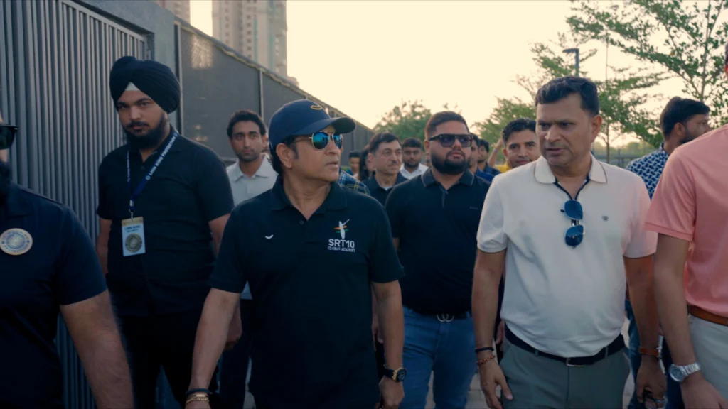 Sachin Tendulkar walking with officials and attendees during his visit to the SRT10 Global Academy in Ahmedabad