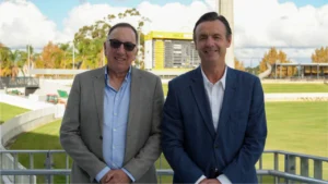 Tim Ungar and John Stephenson standing at the WACA Ground during a WA Cricket meeting, with the cricket field and scoreboard visible in the background.