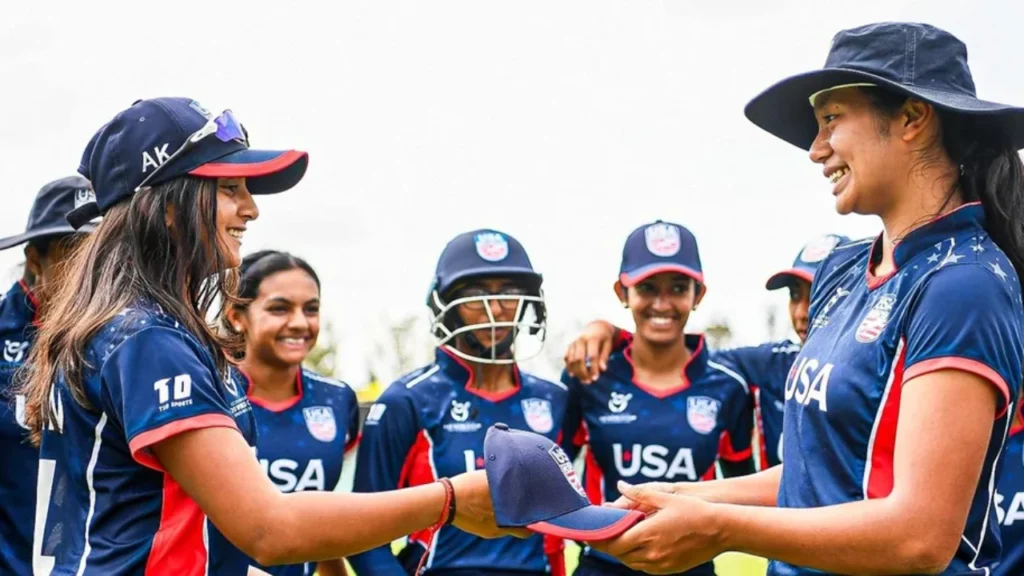 USA Women’s National Team players Anika Kolan and Jivana Aras exchange caps while teammates look on during a team gathering ahead of a cricket match.