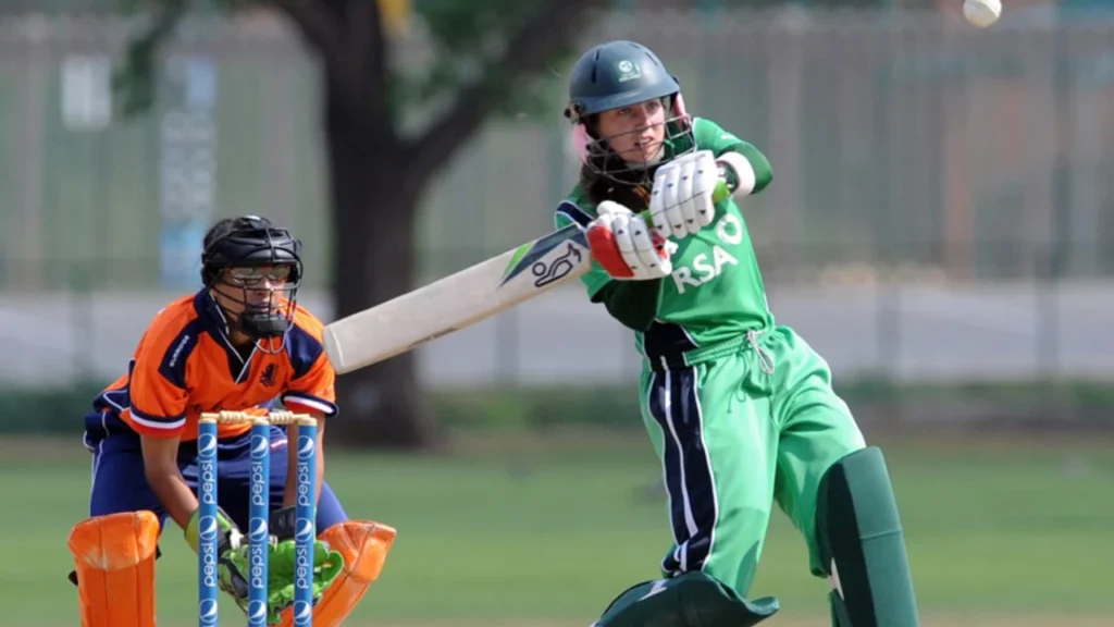 Cecelia Joyce plays an attacking shot for Ireland Women during a cricket match, with the wicketkeeper positioned behind the stumps as the ball travels through the off side.