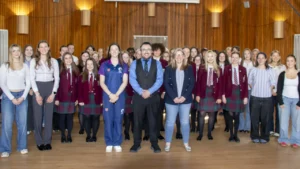 Female choir members and students pose with staff during a recording session of Scotland’s national anthem for the Women’s Rugby World Cup campaign in a school hall.