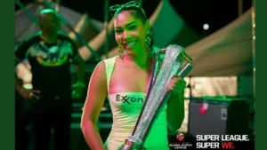 Promotional model holding a cricket-themed trophy during a Guyana Global Super League event under stage lighting, highlighting the tournament's branding and launch activities.