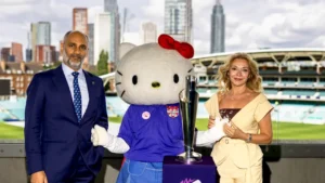 Sanjog Gupta, ICC Chief Executive, and Silvia Figini of Sanrio pose with the Hello Kitty mascot and the Women’s T20 World Cup trophy at a cricket venue.