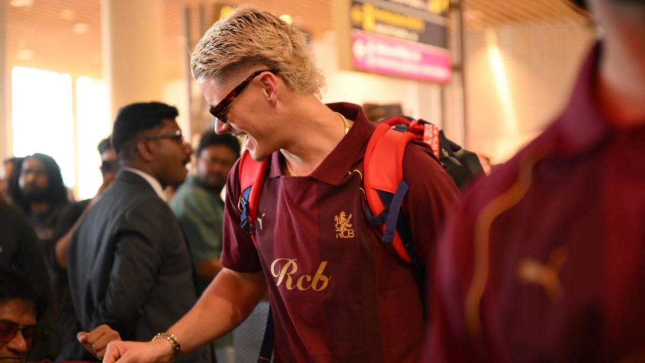 Jacob Bethell arrives with the Royal Challengers Bengaluru squad, wearing an RCB team shirt and backpack during team travel ahead of the 2026 season.