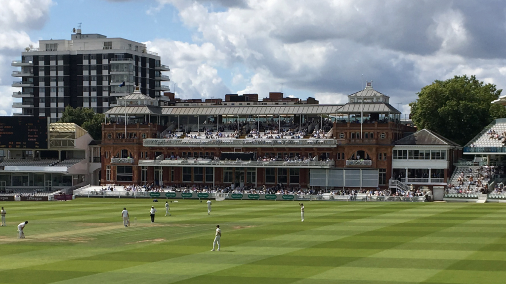 Lord’s Cricket Ground in London during a cricket match, featuring the iconic Pavilion and spectators watching play at the historic home of England cricket.