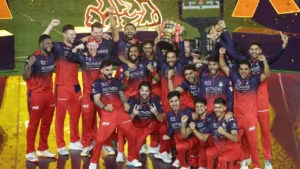 Royal Challengers Bengaluru players celebrate with the IPL trophy after winning the Indian Premier League title, posing together during the championship presentation ceremony.