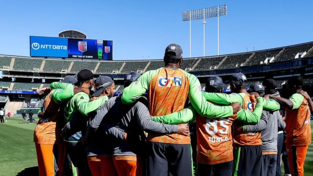 Seattle Orcas players gather in a team huddle on the field before a Major League Cricket match at a packed stadium in the United States.