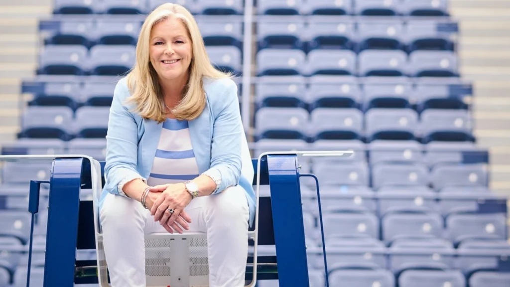 US Open Tournament Director Stacey Allaster poses inside a tennis stadium, seated in front of rows of spectator seats ahead of the tournament.