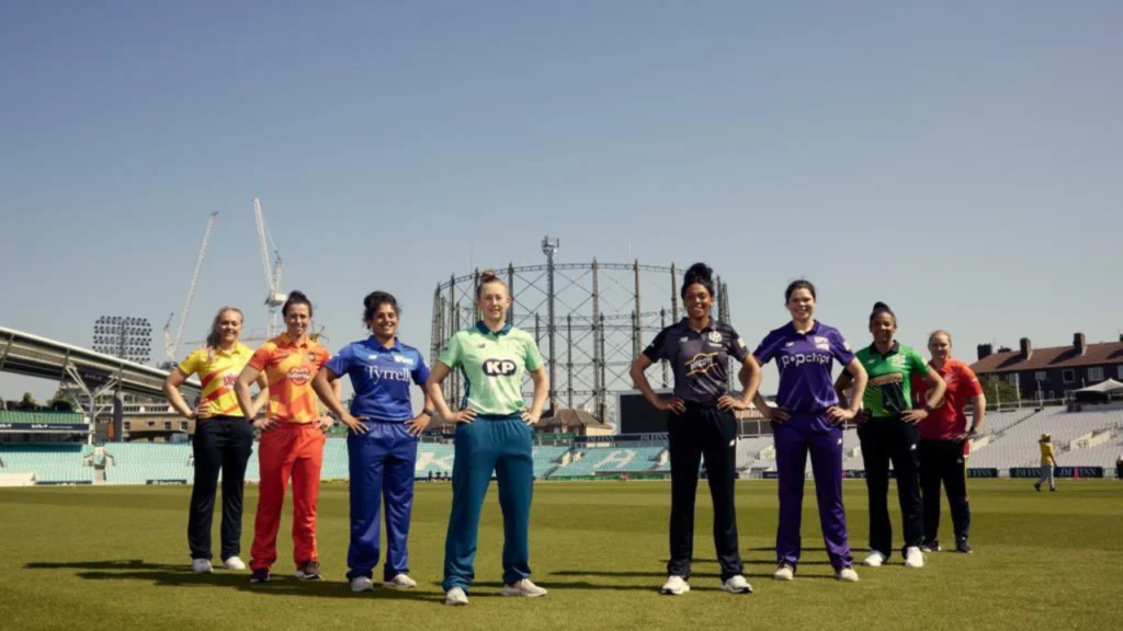 Captains of The Hundred women's teams standing on a cricket field ahead of the tournament season, representing all participating franchises.