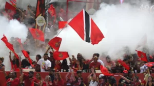 Trinbago Knight Riders supporters waving team flags and the Trinidad and Tobago national flag amid celebrations during a Caribbean Premier League (CPL) cricket match.