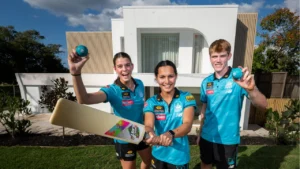 Brisbane Heat players celebrate the club's two-year partnership extension with Plantation Homes while posing with cricket equipment outside a display home.