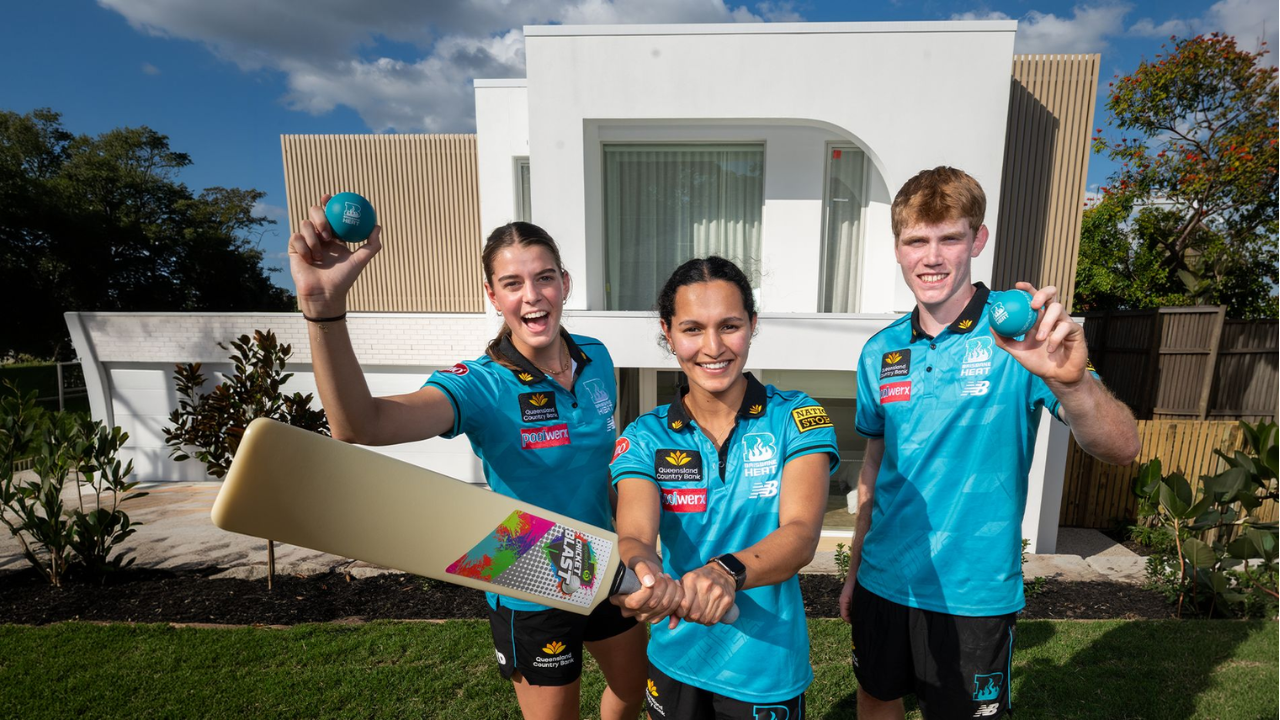 Brisbane Heat players celebrate the club's two-year partnership extension with Plantation Homes while posing with cricket equipment outside a display home.