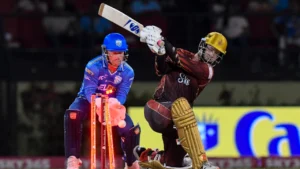 Batter plays an attacking shot during a Caribbean Premier League (CPL) match as the wicketkeeper watches from behind the stumps under floodlights.