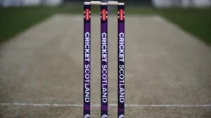 Cricket Scotland branded stumps standing on the pitch at a cricket ground before the start of a match.